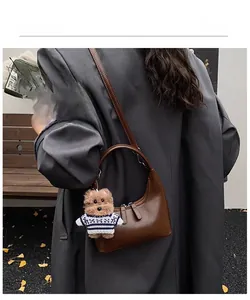 Détail d'un sac demi-lune marron vintage avec un charmant pendentif en peluche