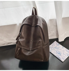 Détail du sac à dos rétro en cuir marron avec poche à rabat et logo sur surface miroir