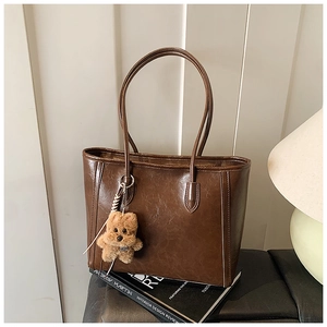 Detail of dark brown oil-wax leather tote bag with a cute plush bear pendant