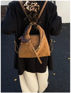 Detail of brown suede backpack with white contrast stitching and dachshund charm