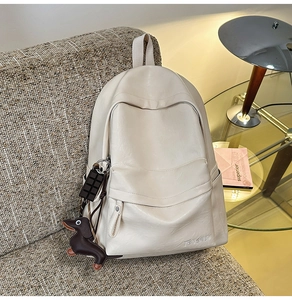 Détail du sac à dos en similicuir blanc crème avec pendentifs mignons sur un canapé