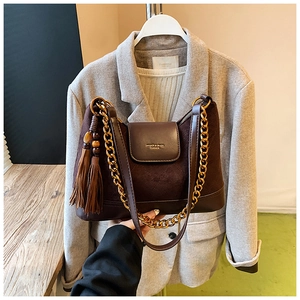 Détail du sac à bandoulière en daim marron avec chaîne dorée et glands décoratifs
