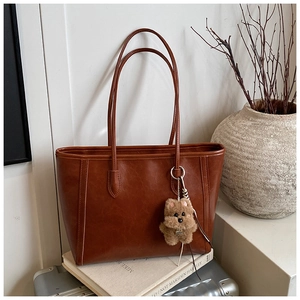 Brown faux leather tote bag with vertical stitching and cute brown plush bear charm detail