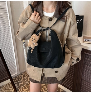 Detailed view of black nylon tote backpack with plush puppy charm and buckle closure