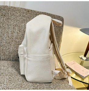 Vue latérale du sac à dos beige en similicuir avec poches sur un canapé gris
