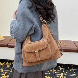 Detail of brown suede Hobo bag with flap pocket and decorative white stitching in autumn setting
