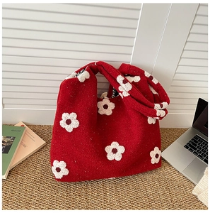 Macro shot of red knitted tote bag with large white floral patterns and thick texture