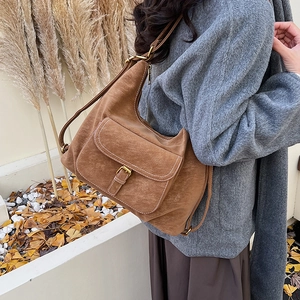 Detail of a brown suede crescent tote bag with contrast stitching and retro buckle