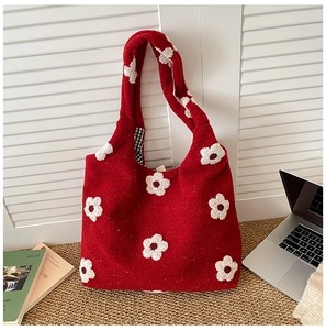 Detail of red felt tote bag with white flower embroidery and classic plaid lining