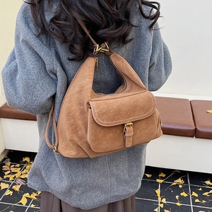 Detail of tan brown textured crossbody bag showing golden metal buckle and retro flap pocket