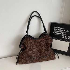 Detailed close-up of leopard print tote bag featuring black embroidery and drawstring detail