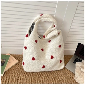 Detail of white fleece tote bag with red heart patterns and black plaid inner lining