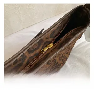 Close-up of golden metal zipper and brown leopard print fabric on underarm tote bag