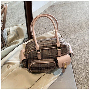 Détail du sac bowling vintage à carreaux avec poignées en cuir rose et poches extérieures