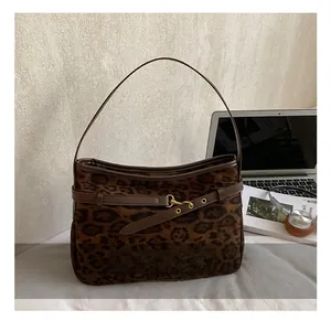 Close-up of leopard print underarm bag with brown leather trim and gold metal buckle