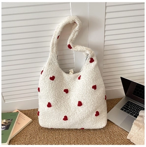 Close-up of fluffy white fleece tote bag with red heart embroidery and wide shoulder strap