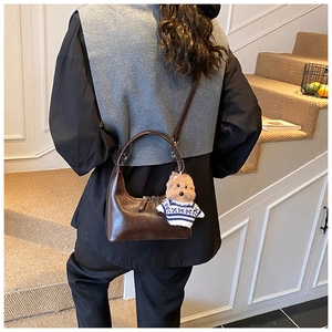 Sac hobo marron foncé rétro avec pendentif chiot porté par un mannequin dans un escalier