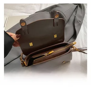 Detailed internal view of brown leather bag with gold hardware and zipper compartments