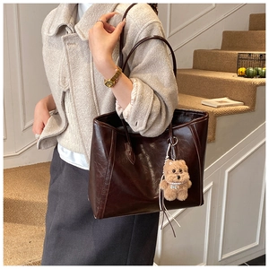 Close-up of vintage brown tote bag with bear charm and pearl necklace detail
