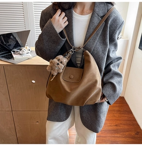 Détail d'un grand sac fourre-tout marron vintage avec pendentif chien en peluche doux