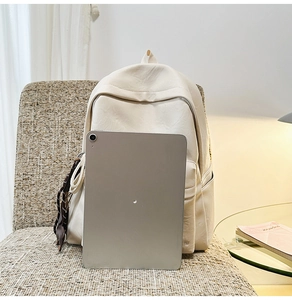 Détail du sac à dos en cuir souple crème avec sangle tressée et poche zippée avant