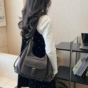 Close-up of dark grey suede hobo tote bag featuring contrast stitching and metal buckle
