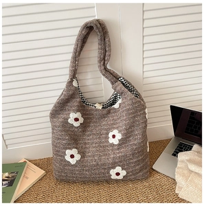 Close-up of brown knit tote bag featuring white floral embroidery and checkered lining