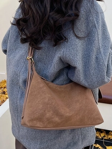 Vintage dark brown suede hobo tote bag with adjustable strap shown on shoulder