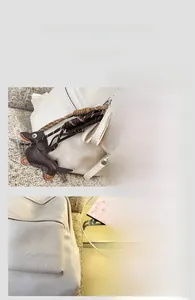 Détail du sac à dos en cuir blanc cassé avec broderie et breloque en forme de teckel