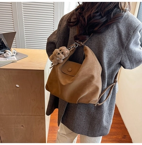 Détail du sac à bandoulière en cuir mat marron avec porte-clés ours en peluche