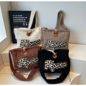 Detail of knit tote bags with Mama leopard patch and horn button closure on stairs