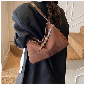 Brown suede hobo bag detail featuring leather shoulder strap and metallic buckle design