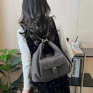 Detail of dark grey suede backpack with white contrast stitching and bronze metal buckle
