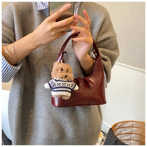 Détail du sac croissant en cuir verni bordeaux avec un joli charm d'ours en peluche