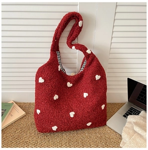 Detail of red teddy fleece tote bag with white heart patch and plaid lining detail