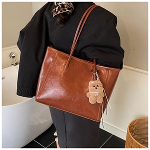 Detail of vintage brown tote bag with glossy oil wax leather and teddy bear pendant