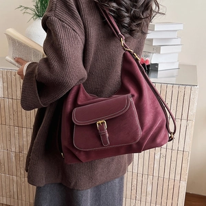 Detail of burgundy large shoulder bag with metal buckle pocket and matte leather texture