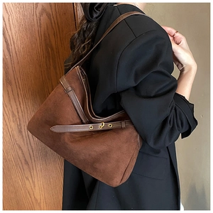 Close-up of vintage brown suede tote bag featuring smooth leather straps and metal hardware