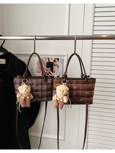 Détail de sacs à bandoulière vintage à carreaux avec anses en cuir et ours