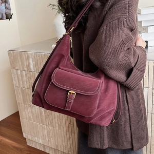 Detail of burgundy leather hobo bag with contrast stitching and vintage gold buckle