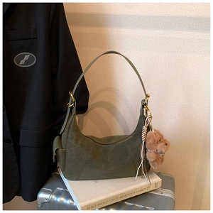Detail of olive green hobo bag featuring plush bear charm and metallic hardware details