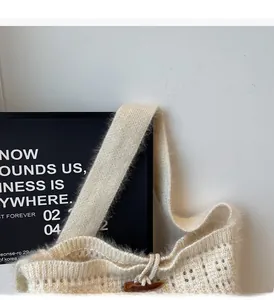 Close-up of cream knit tote bag showing wide shoulder strap and hollow crochet detail