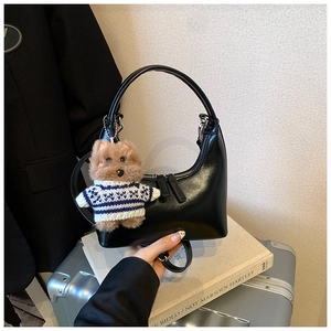 Détail du sac hobo demi-lune noir avec finition brillante et breloque chiot adorable