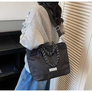 Vue détaillée du sac cabas en nylon noir avec anses tressées et bandoulière réglable