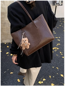 Detail of deep brown tote bag with smooth texture and cute brown plush bear charm