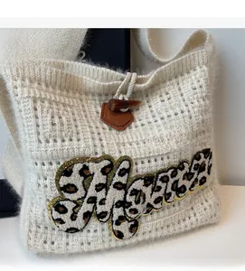Close-up of beige knitted tote bag with leopard print embroidery and toggle closure