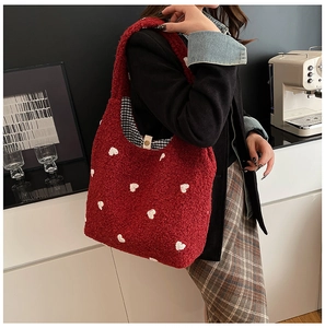 Close-up of red plush tote bag with white hearts and checkered lining with snap closure