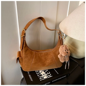 Detail of vintage brown suede crescent shoulder bag with cute plush bear charm