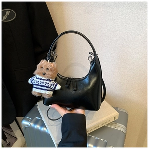 Détail d'un sac hobo en cuir noir mat orné d'un joli pendentif en forme de chien en peluche