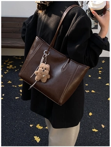 Style de rue d'un sac cabas marron café avec breloque ours sur des feuilles de ginkgo d'automne
